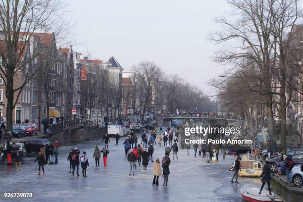 people skate on the frozen prinsengracht canal in amsterdam - amsterdam winter stock pictures, royalty-free photos & images