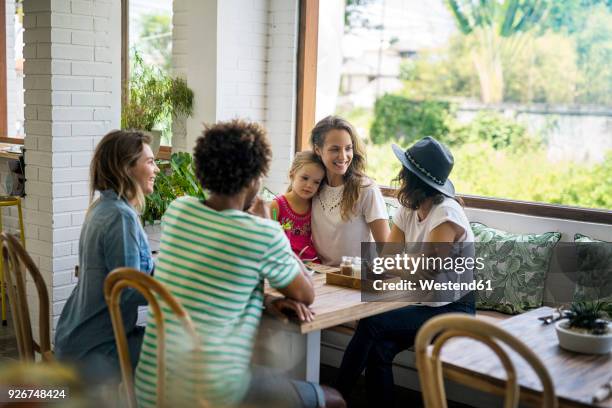 happy friends with child socializing in cozy cafe - asian family cafe stockfoto's en -beelden