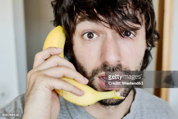 portrait of astonished young man telephoning with banana - cuisine humour stock-fotos und bilder