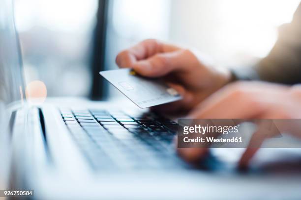man using laptop and holding credit card, close-up - kaufen stock-fotos und bilder