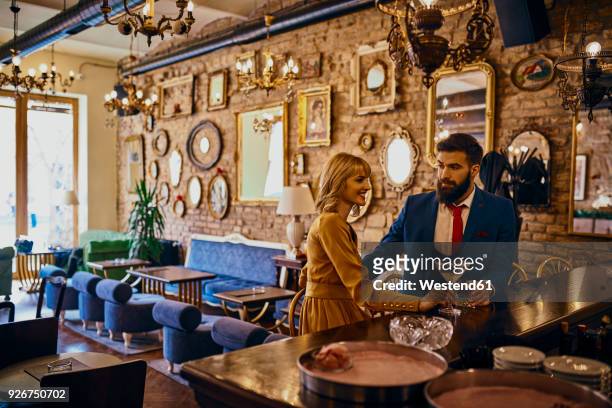 elegant couple having a drink in a bar - whisky bar stock-fotos und bilder