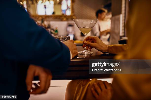 close-up of elegant couple having a drink at the counter in a bar - cocktail counter stock-fotos und bilder