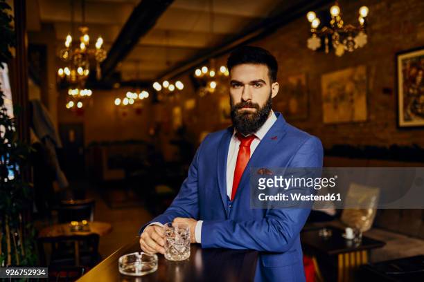 portrait of elegant young man in a bar with tumbler - bar front stock-fotos und bilder