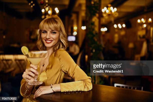portrait of elegant woman with cocktail in a bar - cocktail dress stock-fotos und bilder