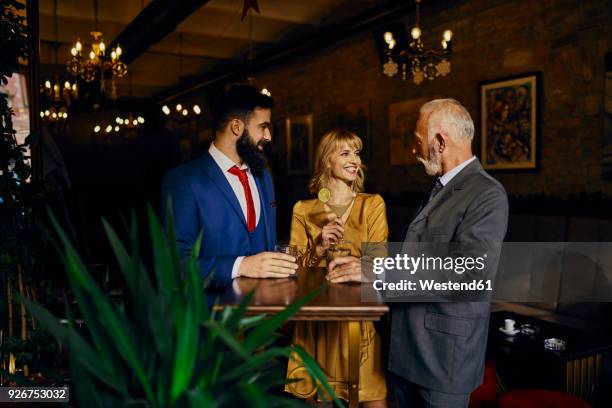 two elegant men and woman socializing in a bar - happy hour stock pictures, royalty-free photos & images