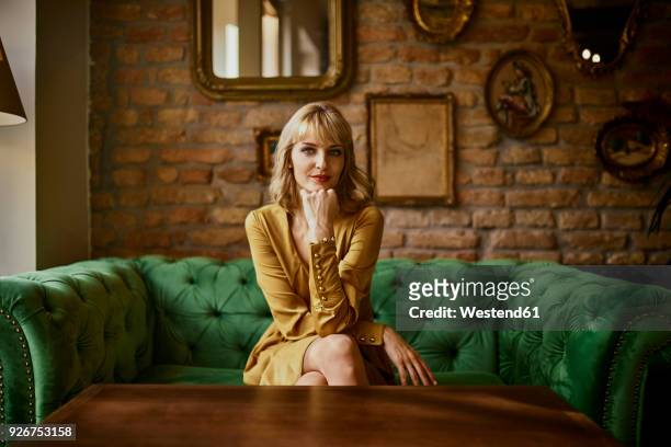 portrait of elegant woman sitting on a couch - abbigliamento elegante foto e immagini stock