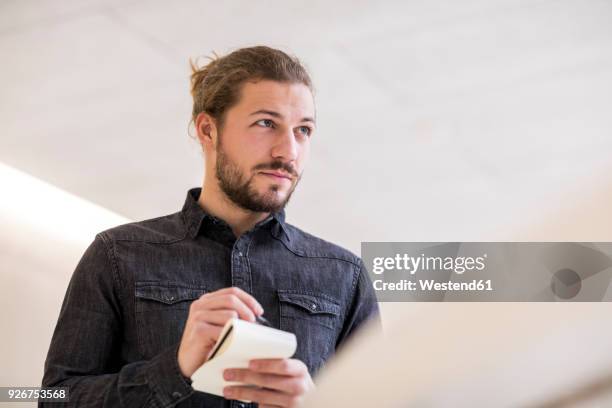 portrait of young man with wrting pad and pencil - periodista fotografías e imágenes de stock