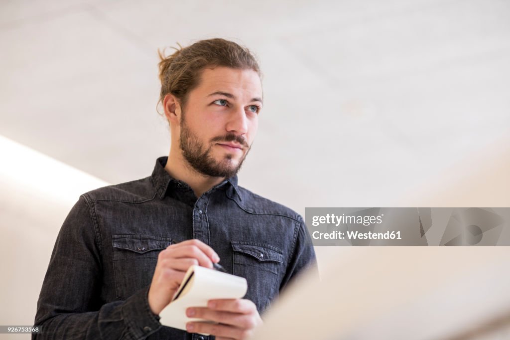 Portrait of young man with wrting pad and pencil