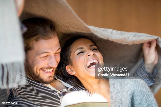 portrait of laughing young couple at home - couple laughing stock-fotos und bilder