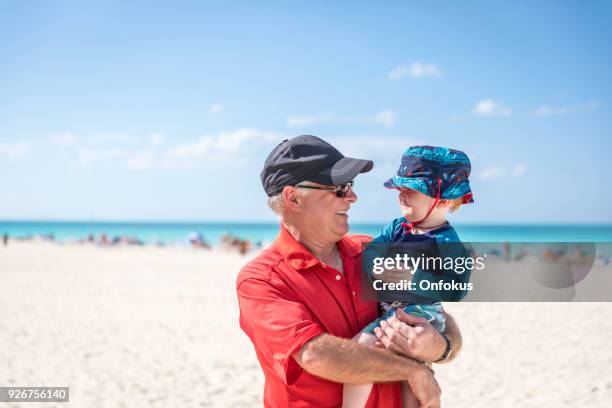 grandfather holding baby boy on tropical beach, cuba - baby grandpa imagens e fotografias de stock