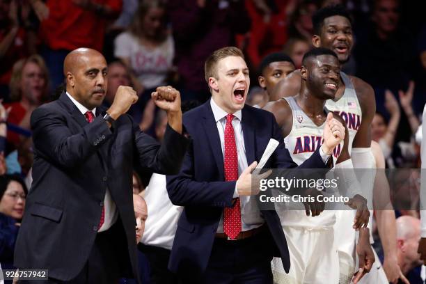 Associate head coach Lorenzo Romar and assistant director of basketball operations Austin Carroll react to a basket during the first half of the...