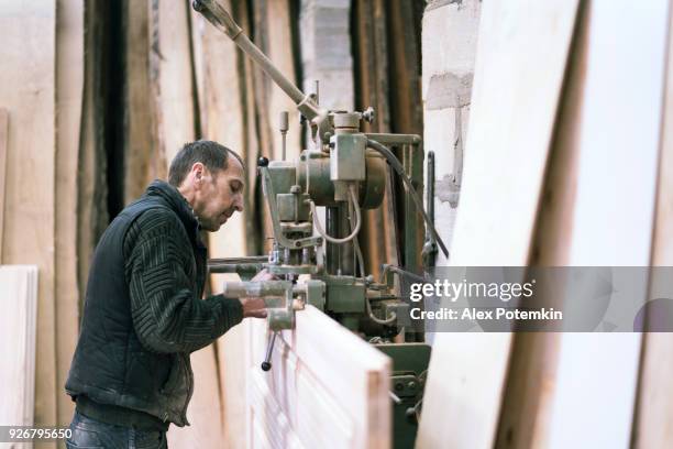 o último homem de 65 anos de idade, sashman e carpinteiro, trabalhar com a máquina de trituração de correntes industriais para a manufatura de madeira pequena - 65 69 years - fotografias e filmes do acervo