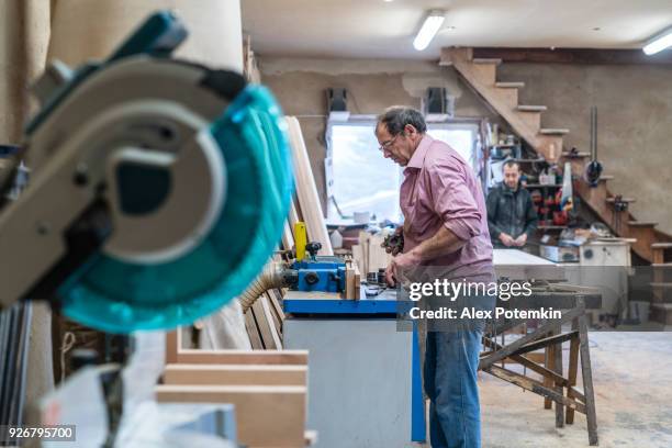 der senior 60 jahre alten mann, tischler und sashman, handwerker, arbeiten mit der industriellen fräsmaschine bei der kleinen holz-fabrik - 55 59 years stock-fotos und bilder