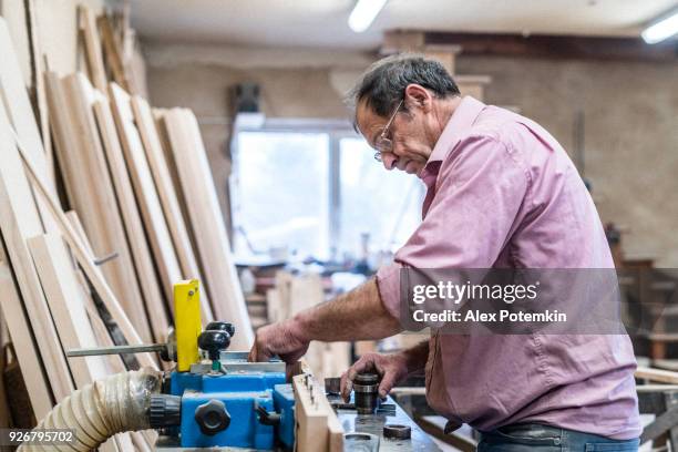 der senior 60 jahre alten mann, tischler und sashman, handwerker, arbeiten mit der industriellen fräsmaschine bei der kleinen holz-fabrik - 55 59 years stock-fotos und bilder