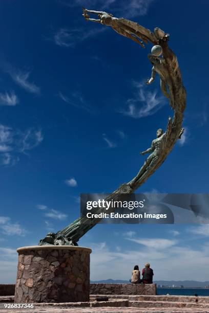 Two tourists under the Millennia sculpture of human history on the Malecon Puerto Vallarta Mexico.