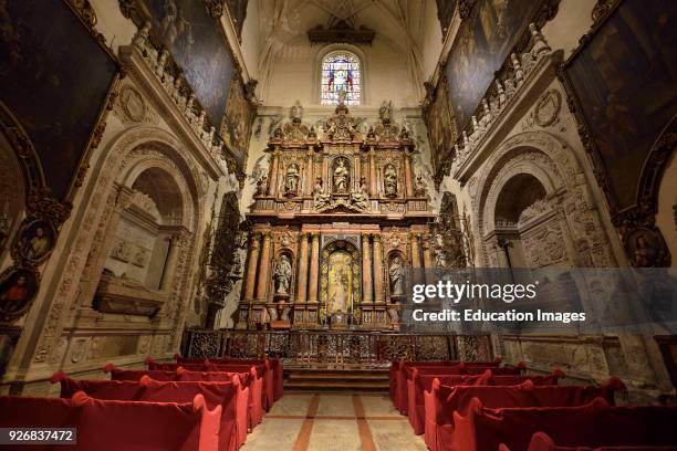 Ornate side chapel of the Virgin of Antigua with red covered pews at the Seville Cathedral.