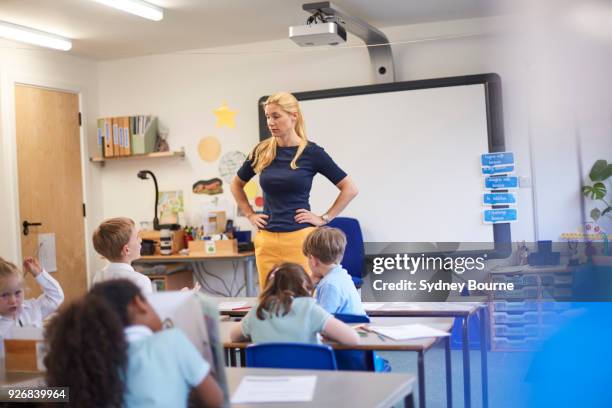 teacher with hands on hips in front of class at primary school - teacher in front of class stock pictures, royalty-free photos & images