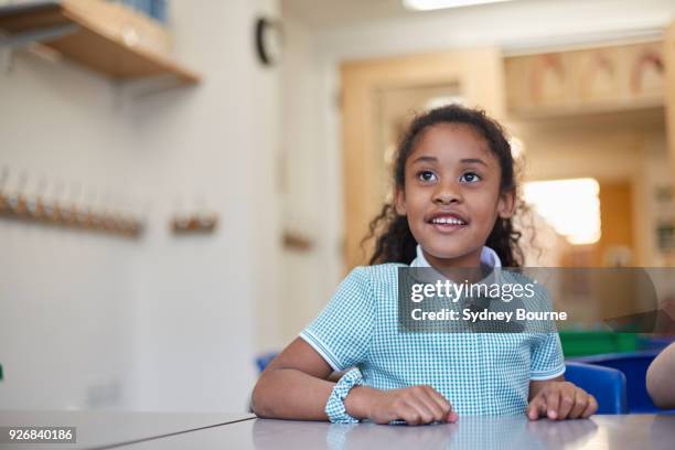 schoolgirl listening in classroom lesson at primary school - primary school children in uniform stock pictures, royalty-free photos & images