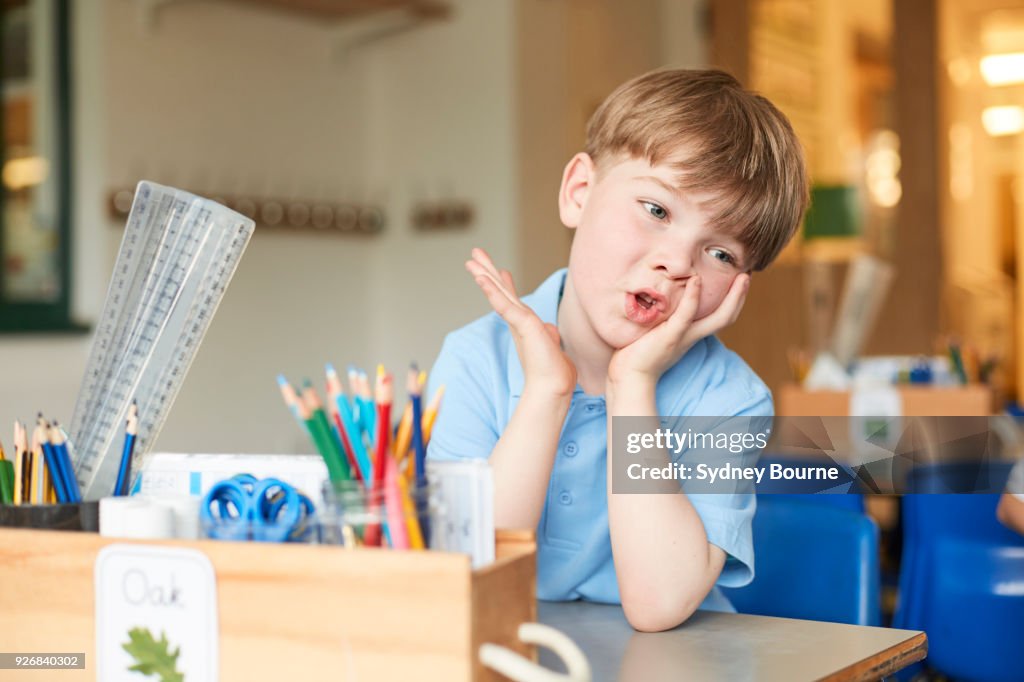 Bored primary schoolboy at classroom desk