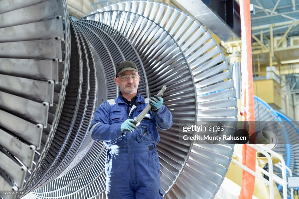 Portrait of engineer with turbine blade in turbine maintenance factory