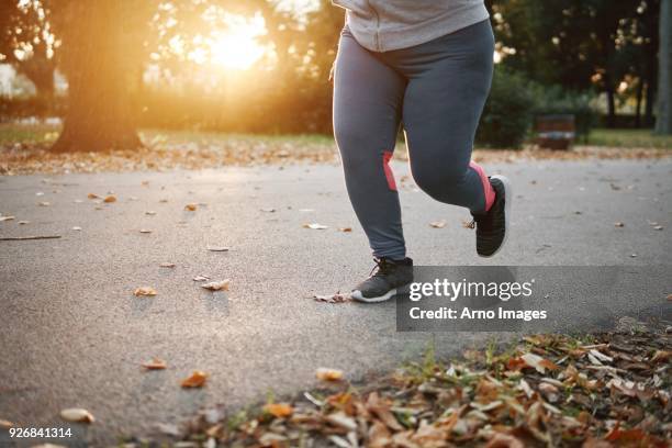 curvaceous young female runner running in park, waist down - fett stock-fotos und bilder