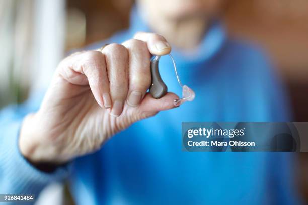 senior woman holding hearing aid, close-up - hearing loss stock pictures, royalty-free photos & images