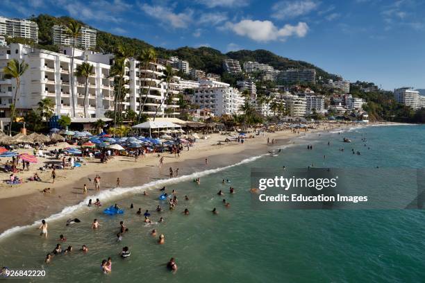 Locals and tourists swimming in the Pacific ocean at Los Muertos beach Puerto Vallarta Mexico.