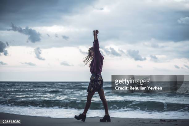 young woman walking on beach with arms raised at dusk, odessa oblast, ukraine - ankle length stock pictures, royalty-free photos & images