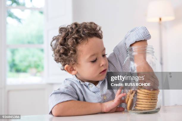 boy getting biscuit from cookie jar - child cookie jar stock pictures, royalty-free photos & images