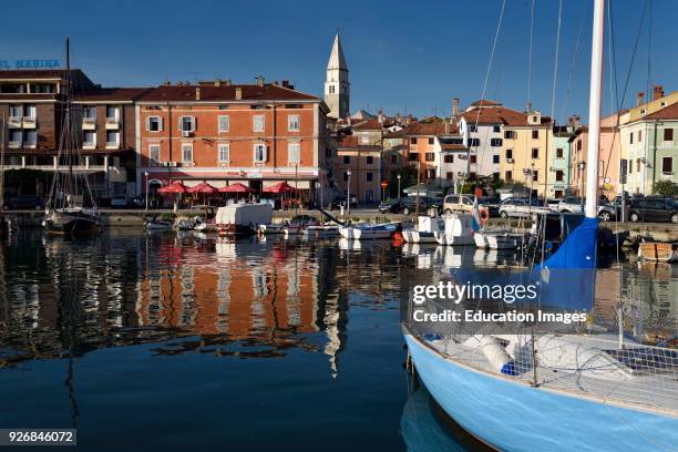 Marina at old fishing town of Izola Slovenia on the Adriatic coast with Parish Church of St Maurus tower and colorful reflected buildings.