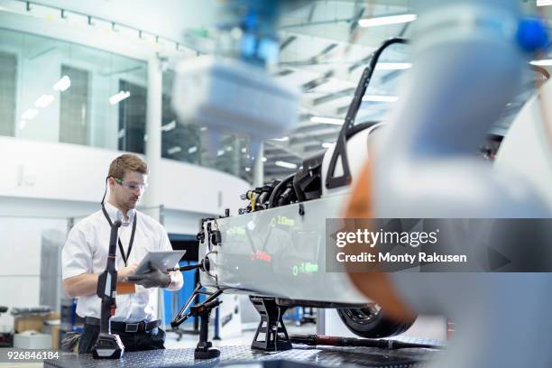 engineer and robot inspecting car in robotics research facility - véhicule motorisé photos et images de collection
