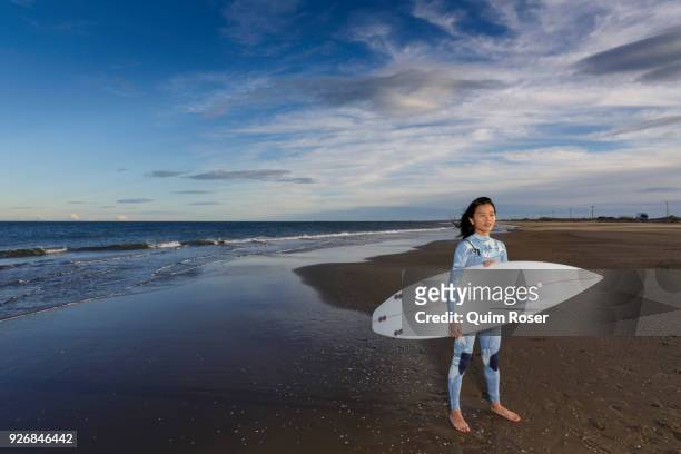 portrait of young female surfer standing on beach, tarragona, catalonia, spain - beach holding surfboards stock pictures, royalty-free photos & images