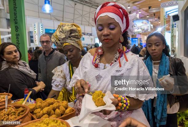 Visitors are served Bahia dishes by a women wearing traditional garb at the Brazil stand in BTL "Bolsa de Turismo Lisboa" trade fair on March 03,...