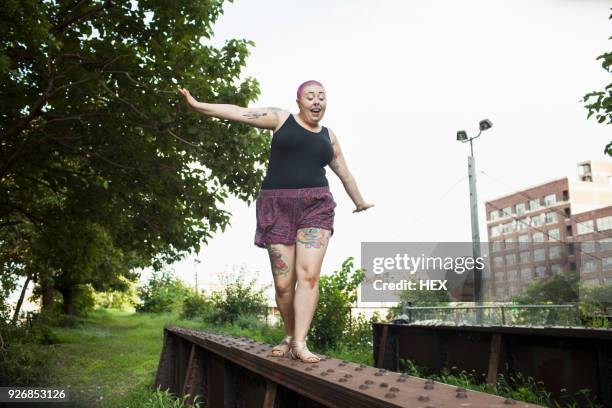 a young woman balancing on a bench - ladies shorts stockfoto's en -beelden