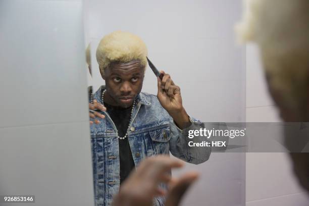 a young man getting ready in the mirror - combing stock pictures, royalty-free photos & images