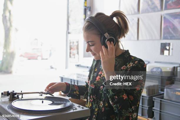 young woman listening to record in a record store - headphones turntable stock-fotos und bilder
