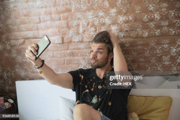 young man taking a selfie on his bed - duck face selfie stock pictures, royalty-free photos & images