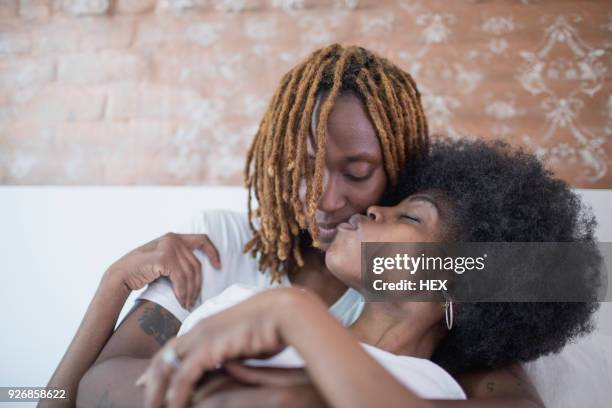 lesbian couple embracing on bed - black lesbians kiss stock pictures, royalty-free photos & images