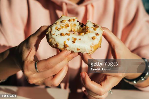 woman eating a doughnut - eating donuts stockfoto's en -beelden