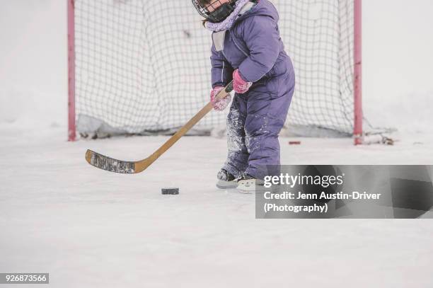 young girl playing ice hockey, preparing to hit puck, mid section - hockey stick and puck stock pictures, royalty-free photos & images