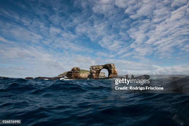 people in boat by darwins arch, darwin island, seymour, galapagos, ecuador, south america - darwin island fotografías e imágenes de stock