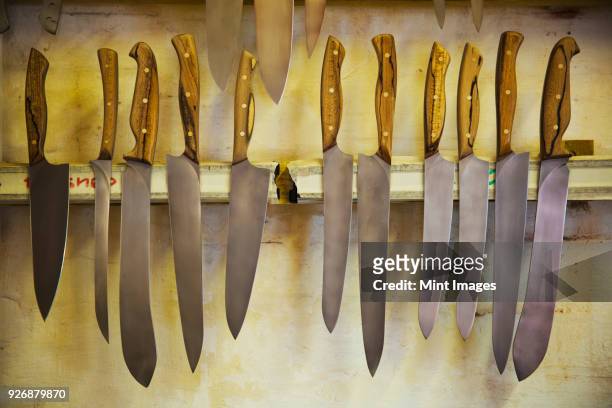 knives with shaped wooden handles and a variety of shaped blades on magnetic knife holder in a workshop. - magnetwand stock-fotos und bilder