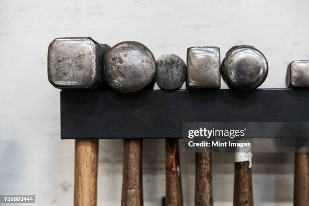 close up of a selection of hammers hanging on a wall in a metal workshop. - sledgehammer stockfoto's en -beelden