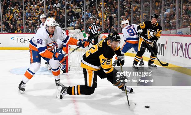 Patric Hornqvist of the Pittsburgh Penguins handles the puck against Adam Pelech of the New York Islanders at PPG Paints Arena on March 3, 2018 in...