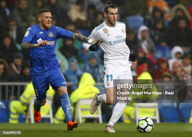 Gareth Bale of Real Madrid competes for the ball with Vitorino Antunes of Getafe during the La Liga match between Real Madrid and Getafe at Estadio...