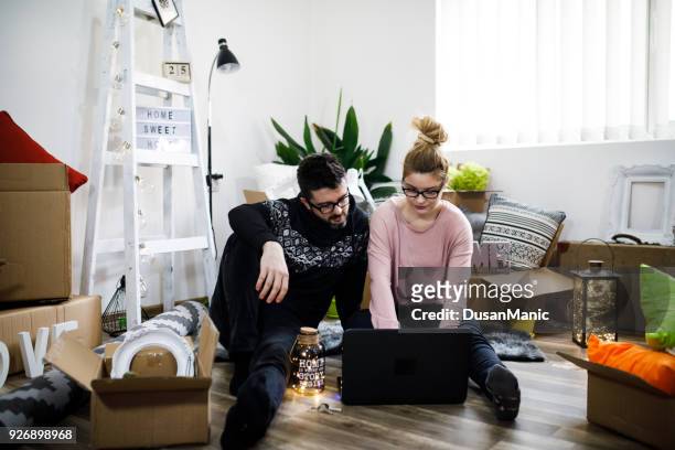 young couple moving in new home.sitting on floor and relaxing after cleaning and unpacking.looking something on laptop. - unfurnished stock pictures, royalty-free photos & images