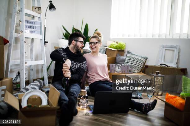 young couple moving in new home.sitting on floor and relaxing after cleaning and unpacking.looking something on laptop. - unfurnished stock pictures, royalty-free photos & images