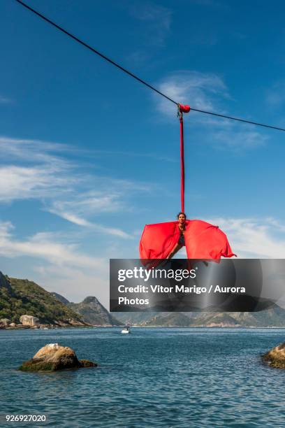 woman doing aerial acrobatics hanging from highline in rio de janeiro, brazil - waterline stock pictures, royalty-free photos & images