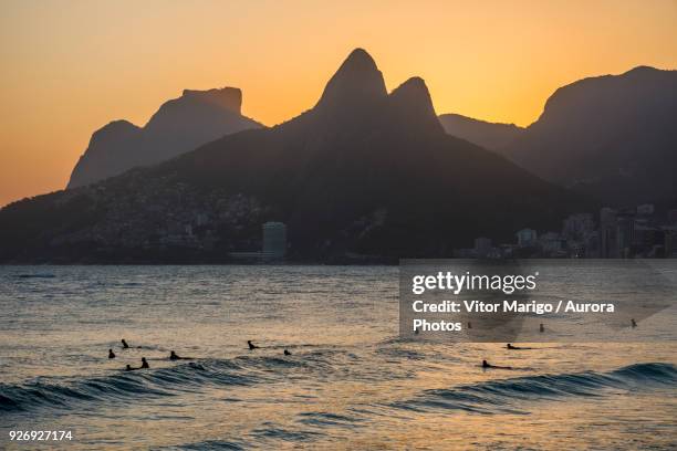 surfers on water during sunset in arpoador beach, next to ipanema in rio de janeiro, brazil - touristical stock pictures, royalty-free photos & images