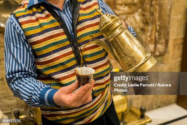 man pouring cup of traditional arabic tea from dallah, amman, jordan - amman foto e immagini stock